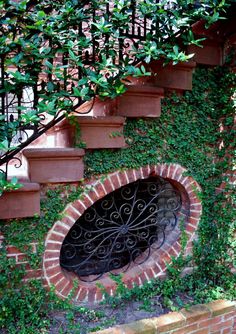 an iron door is surrounded by ivy on the side of a brick wall and stairs