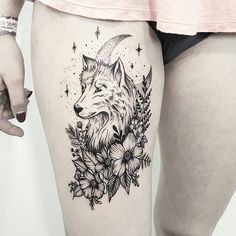 a woman's thigh with a tattoo of a wolf and flowers on the side