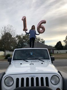 a woman standing on top of a white jeep with the number 16 in front of her