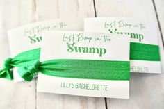 two green ribbons tied to each other on top of white wood planks with the words swamp written on them