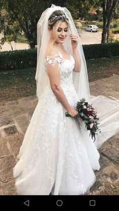 a woman in a wedding dress posing for the camera with her veil pulled back over her shoulder