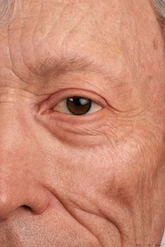 an older man with wrinkles on his face and eye looking at the camera, close up