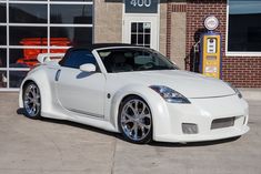 a white sports car parked in front of a gas station