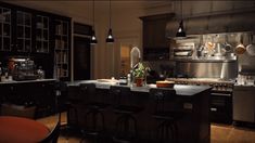 a large kitchen with lots of counter space and lights hanging from the ceiling above it