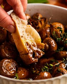 someone is dipping some bread into a bowl of mushrooms