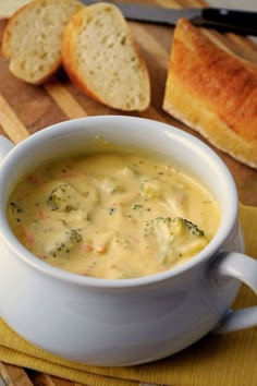 a white bowl filled with soup on top of a wooden cutting board next to bread