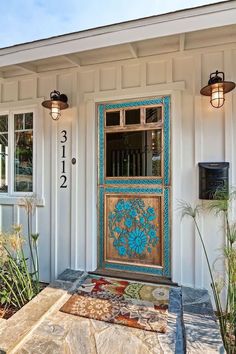 the front door of a house with blue flowers painted on it and two lights above