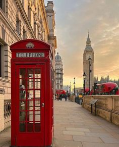 a red phone booth sitting on the side of a road