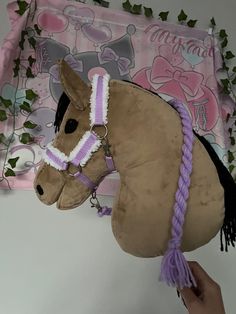 a stuffed horse head is being held up by a person's hand with pink and white trim