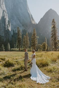 a bride and groom standing in front of a mountain