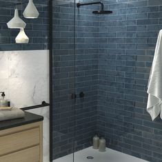 a bathroom with blue tiled walls and white towels hanging on the shower head, along with black counter tops