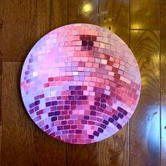 a pink and purple mosaic plate sitting on top of a wooden floor next to a wall