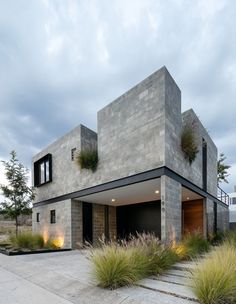 a concrete house with plants on the front