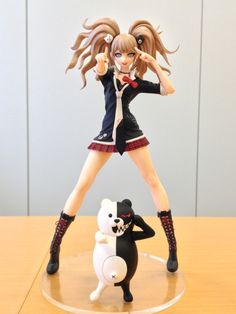 a figurine is posed on a table with a cat and panda doll next to it