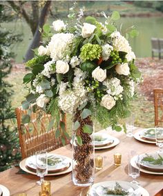 a vase filled with white flowers sitting on top of a table next to plates and glasses