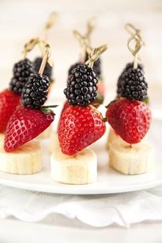 four small fruits are placed on banana slices and garnished with blackberries, raspberries, and bananas