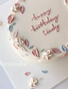 a birthday cake decorated with flowers and leaves