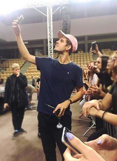 a man standing in front of a crowd holding up his cell phone