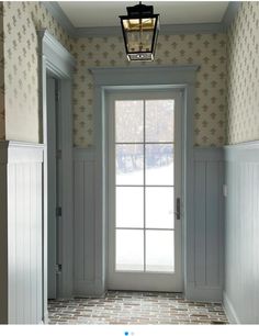 an open door leading into a room with white paneling and wallpaper on the walls