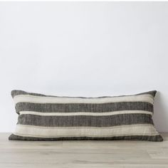 a black and white striped pillow sitting on top of a wooden floor next to a wall