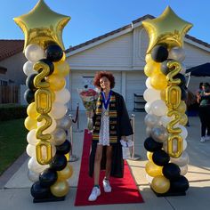 a woman is standing in front of some balloons on the red carpet outside her house