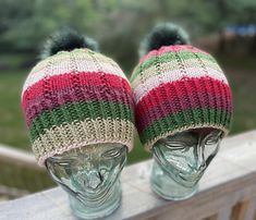 two knitted hats sitting on top of a glass head mannequin's head