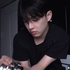 a young man sitting at a table with a camera in his hand and looking down