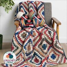 a crocheted blanket sitting on top of a chair next to a potted plant