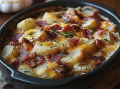 a casserole dish with potatoes, bacon and cheese in it on a wooden table