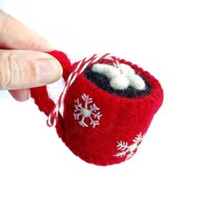 a hand is holding a small red ornament with snowflakes on it