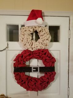 a wreath with a santa hat hanging on the front door