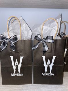 two brown paper bags with black and white bows are sitting side by side on a table