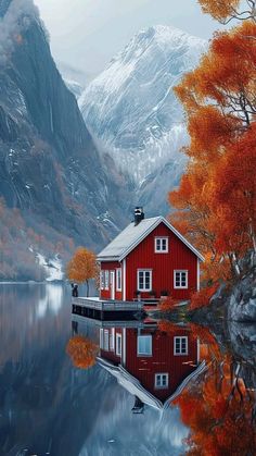 a red house sitting on top of a lake surrounded by mountains