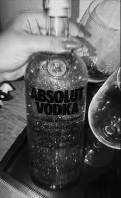 a bottle of absolut vodka sitting on top of a table next to glasses