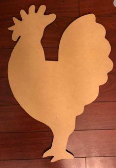 a cutout of a chicken on a wooden floor with the word rooster written below it