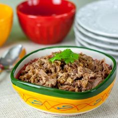 a colorful bowl filled with meat and garnished with cilantro on top