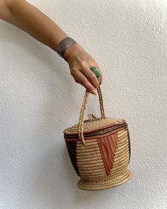 Top handled basket purse with lid that comes off. Likely African made by hand. Era unknown. Perfect size holds all the essentials. Use to carry or as a display & storage vessel. Measurements: 6 inches height | 7 inches wide | 7 inch drop handle Natural Basket-shaped Bucket Bag With Detachable Handle, Natural Color Basket-shaped Bucket Bag With Detachable Handle, Gift Bucket Straw Bag With Handles, Brown Basket Shaped Straw Bag With Top Carry Handle, Brown Basket-shaped Straw Bag With Top Carry Handle, Brown Basket Straw Bag With Detachable Handle, Amp Storage, Basket Purse, Display Storage