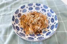 a blue and white bowl filled with oatmeal on top of a table