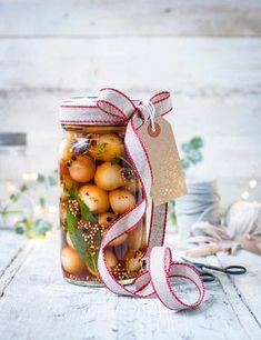 a jar filled with lots of fruit sitting on top of a wooden table next to scissors