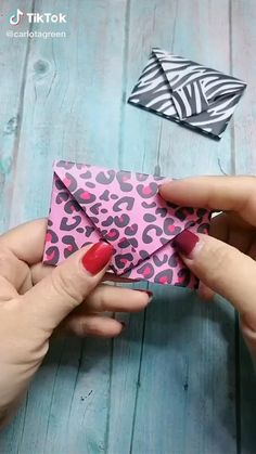 two hands holding an origami animal print envelope