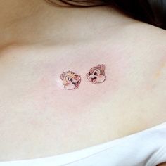 a woman's chest with two small cartoon bears on the left side of her breast