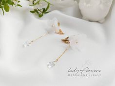 two white flowers are sitting next to each other on a white cloth with gold accents