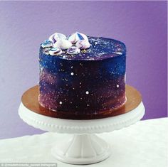 a blue and purple cake sitting on top of a white table next to a purple wall