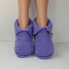 a doll's feet wearing purple slippers with a bow on the front and bottom