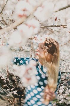 a woman standing in front of a tree with white flowers