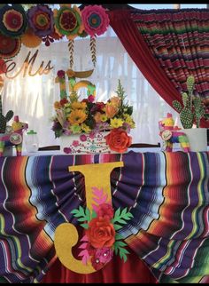 the table is decorated with colorful paper flowers and decorations for a mexican themed birthday party