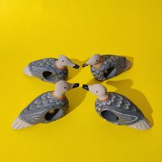 four ceramic ducks sitting on top of a yellow surface