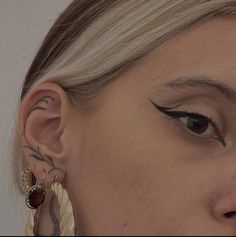 a close up of a person with ear piercings and tattoos on their ears,