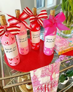 three wine bottles with hearts on them are sitting on a table next to books and flowers