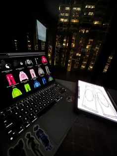 an open laptop computer sitting on top of a desk next to a lit up keyboard